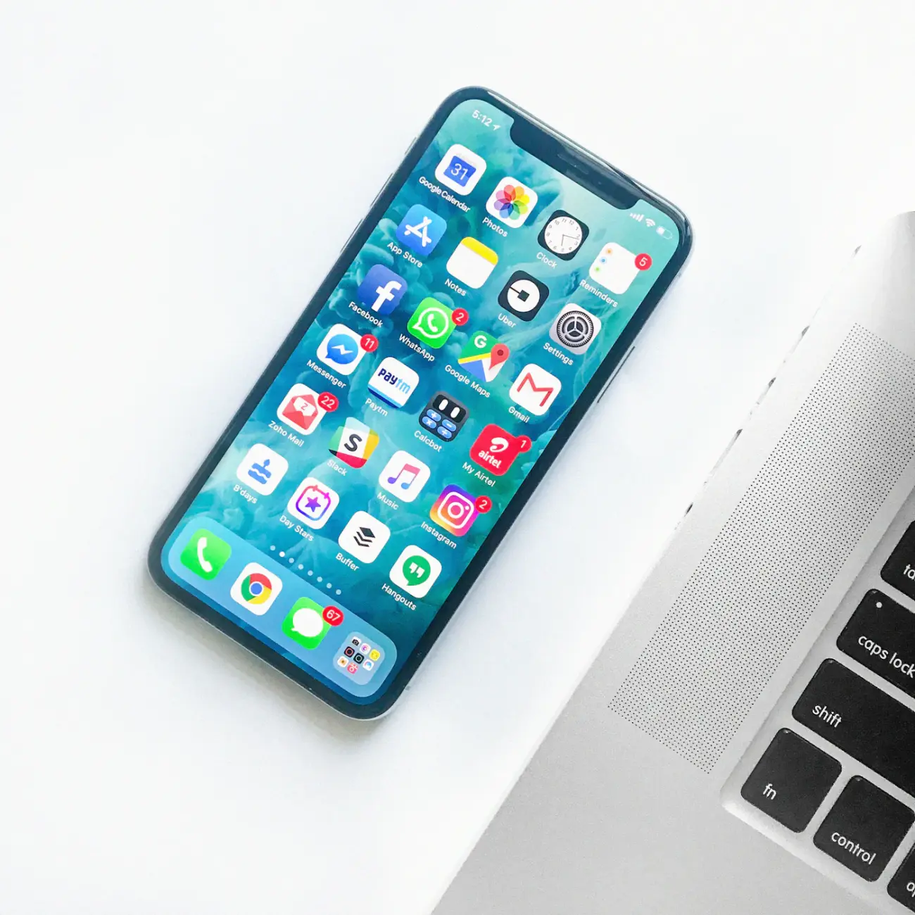 Uno smartphone appoggiato a un portatile mostra la griglia delle applicazioni installate